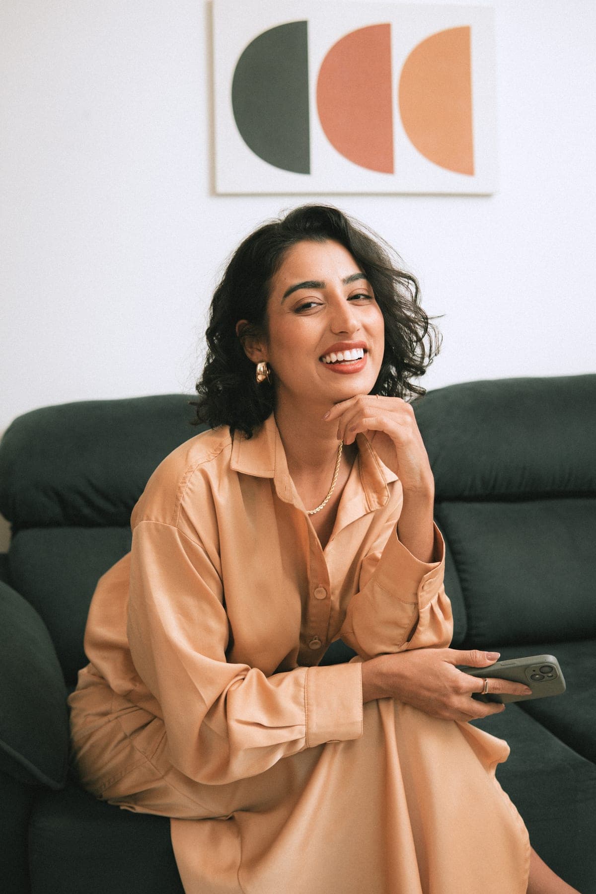 Bia Cintra sorrindo, sentada num sofá verde